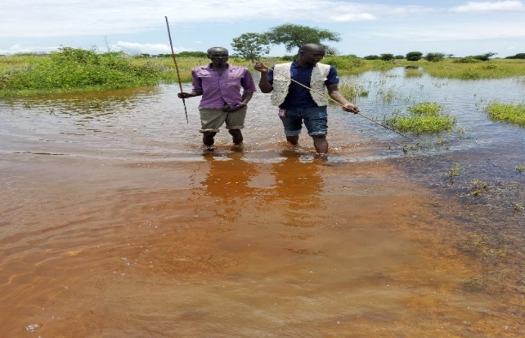 BHI coordinator for Lot 18 with James the BHW walking on a flooded road in Agaal boma